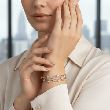 Woman wearing a gold bracelet with clear stones against a blurred indoor background